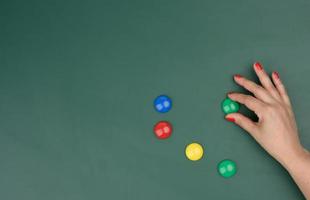 female hand attaches multi-colored magnets to a green board photo