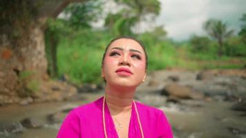 Asian women with makeup and pink dresses enjoying the village view near the river while wearing golden jewelry video