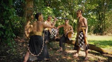 A man with a golden costume and golden crown talks to a group of a man near the green tree video