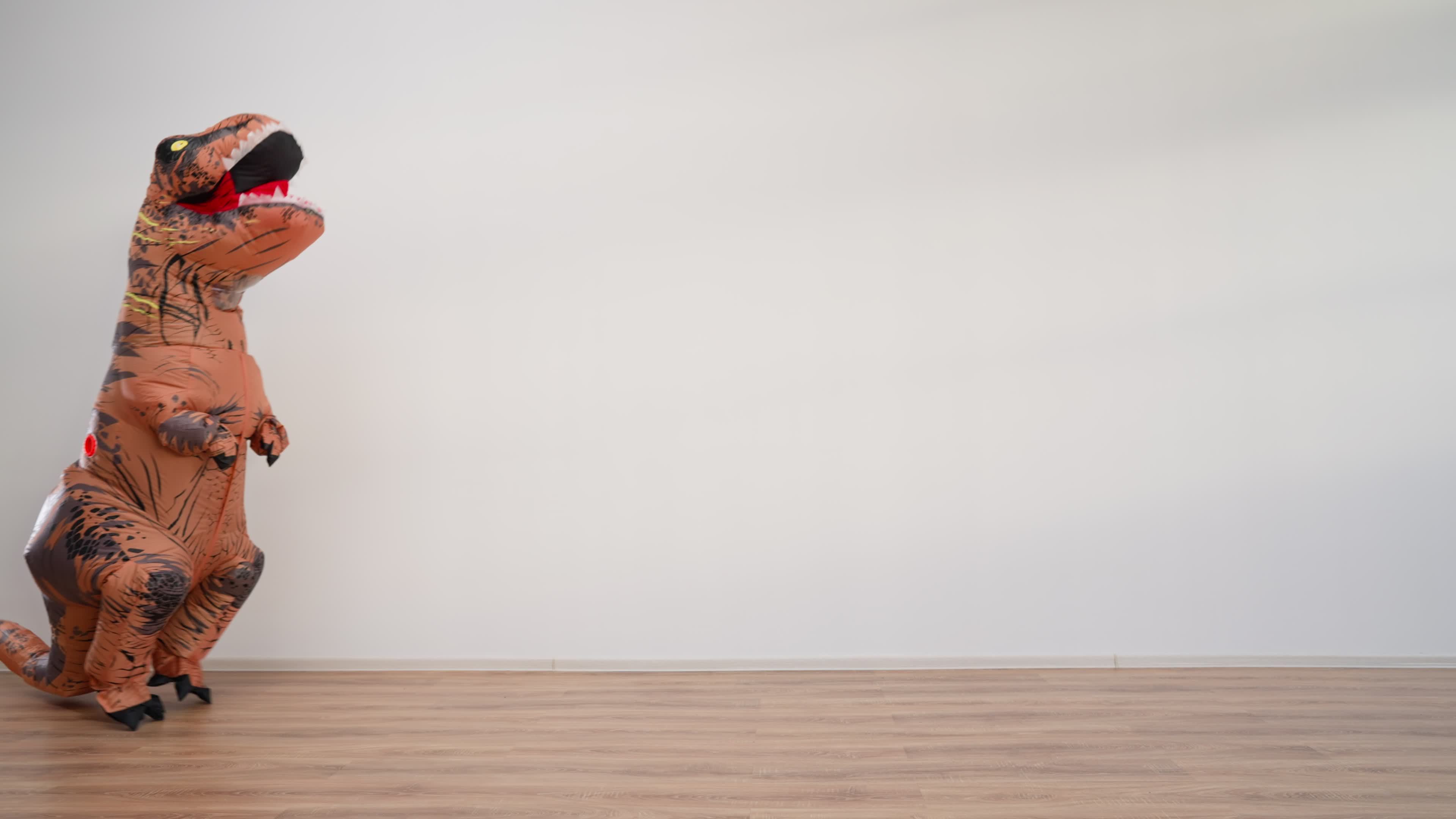 Happy Man in a Funny Dinosaur Costume is Dancing on a White Background