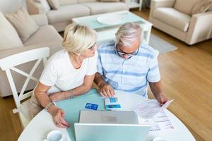 Senior couple smiling checking utility bills or insurance at computer with easy access, elderly users of technology photo