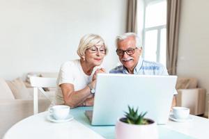 Happy old family couple talking with friends and family using laptop , surprised excited senior woman looking at computer waving and smiling. photo