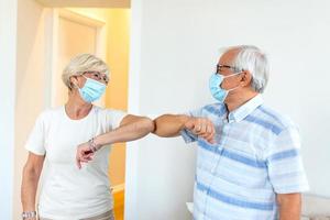 amigos mayores sonrientes y amistosos que mantienen la distancia social, saludándose unos a otros golpeándose los codos en lugar de abrazos o apretones de manos, evitando la propagación de la infección por el coronavirus covid 19. foto