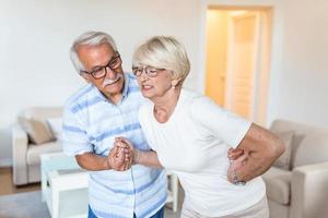 Senior couple at home. Handsome old woman is having back pain and her attractive old husband supports her. photo