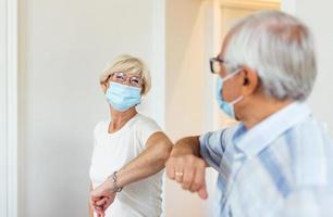 amigos mayores sonrientes y amistosos que mantienen la distancia social, saludándose unos a otros golpeándose los codos en lugar de abrazos o apretones de manos, evitando la propagación de la infección por el coronavirus covid 19. foto