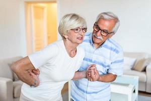 Senior couple at home. old woman is having back pain and her attractive old husband supports her. photo