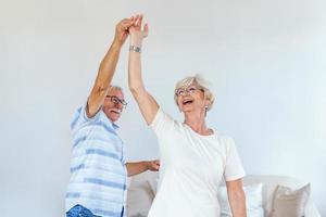 Love lives forever Senior couple at home. Handsome old man and attractive old woman are enjoying spending time together while dancing. photo