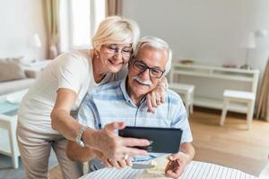 cónyuges ancianos en el hogar. la esposa abraza al esposo. tener una conversación agradable chateando en una videollamada con hijos y nietos adultos usando una tableta foto