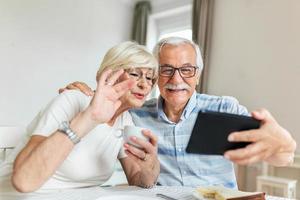 pareja mayor sonriendo y mirando la misma tableta abrazada. concepto interior, en casa. hombre y mujer maduros y jubilados que usan tecnología - estilo de vida de bloqueo y cuarentena foto