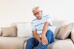 dolor en la pierna de un anciano. hombre mayor que sostiene dolor muscular doloroso, esguince o calambre foto