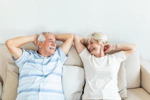 Calm senior mature couple relaxing on soft comfortable sofa having daytime nap together, carefree middle aged old family breathing fresh air enjoying no stress free peaceful weekend resting on couch photo