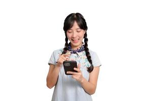 retrato de una feliz y hermosa joven asiática vestida de mezclilla usando un smartphone con fondo blanco. foto de estudio