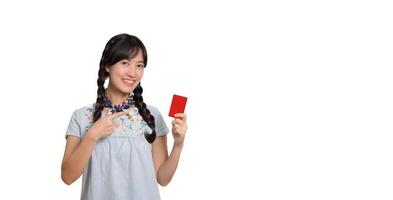 Portrait of beautiful happy young asian woman in denim dress holding credit card on white background photo