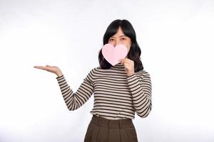 hermosa joven asiática sosteniendo un corazón de papel mientras se enfrenta a un fondo blanco. hermosa joven asiática con corazón de papel. foto