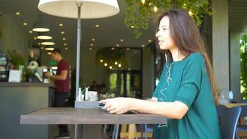 jung Frau Berufung mit Telefon während Sitzung allein im Kaffee Geschäft während Sommer- Tag. video