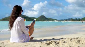 jeune femme avec smartphone pendant les vacances à la plage tropicale. belle fille sur la plage avec téléphone portable sur l'île des caraïbes. ralenti video