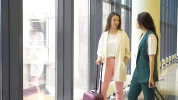 mulheres jovens com bagagem no aeroporto internacional andando com sua bagagem. passageiros da companhia aérea em um saguão do aeroporto à espera de aeronaves de voo video