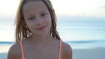 Portrait of little girl looking at camera and smiling background beautiful sky and sea. SLOW MOTION video