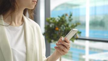 Portrait of young woman with smartphone in international airport. Airline passenger in an airport lounge waiting for flight aircraft video