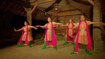 los javaneses bailan juntos con un vestido naranja y una bufanda verde mientras el festival comienza dentro del pueblo video