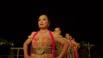 A Group of Javanese dancers standing together before dancing on the stage with orange dresses in warm lighting video