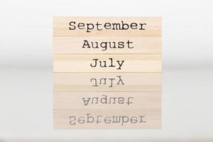 de madera cubo con el inscripción julio, agosto, septiembre en un blanco antecedentes foto