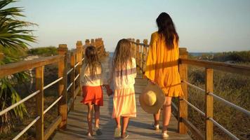 Adorable little girls and young mother walking on white beach in the evening video