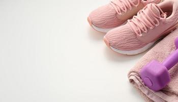 pair of pink sneakers, a terry towel and a plastic dumbbell on a white background photo