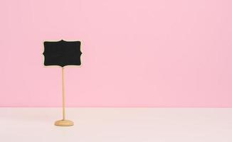empty wooden pointer on a stick for writing text, pink background photo