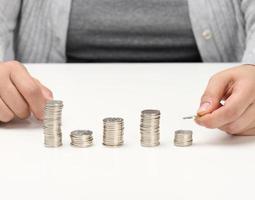 mujer mano pone dinero en un pila de dinero. dinero ahorro concepto. foto