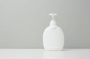 White plastic container with a pump for cosmetic liquid, liquid soap photo