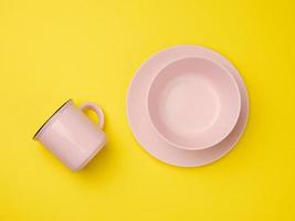 pink ceramic mug and empty ceramic plate on yellow background, top view photo