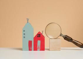 magnifier and wooden house on a brown background. Real estate rental, purchase and sale concept. Realtor services, building repair and maintenance photo