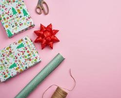rolls with wrapping paper, brown rope, scissors, decor and a wrapped square box with a gift photo