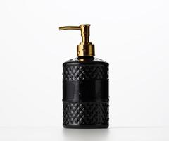 black plastic container with a golden dispenser on a white background. Container for liquid soap, shampoo photo