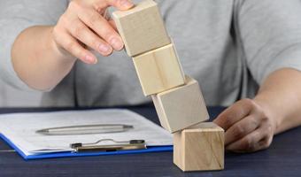 female hand holds falling cubes on the table. The concept of a manager's crisis photo