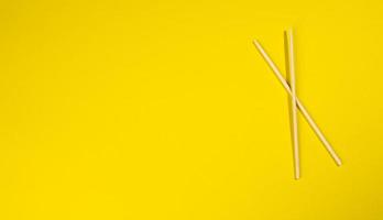 two wooden chopsticks on a yellow background photo