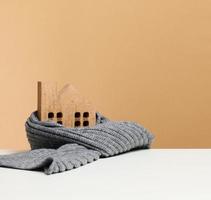 wooden miniature house wrapped in a gray knitted scarf. Building insulation concept, loans for repairs photo