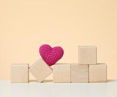 Red knitted heart and wooden cubes. Donation concept, love photo