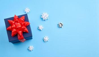 dark blue cardboard gift square box, red bow, ribbons on a blue background photo