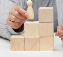 pyramids from wooden cubes and figurines of men on the table. The concept of achieving goals, moving up the career ladder. Detection of single-minded personality photo