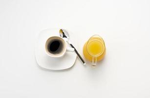 freshly squeezed juice in a glass transparent decanter, a cup of coffee, honey and oatmeal on a white table. Morning breakfast photo