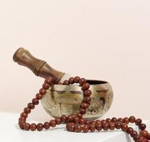 copper singing bowl and wooden clapper on a white table. Musical instrument for meditation, relaxation, various medical practices related to biorhythms, normalization of mental health photo