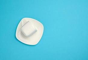 empty white ceramic cup and saucer on blue background, top view photo