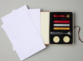 white envelope and items for sealing with wax seal on gray background photo