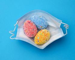 decorative easter eggs lie in a disposable medical mask on a blue background photo