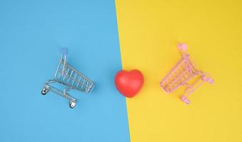 corazón rojo en un carro de metal en miniatura de la tienda sobre un fondo gris. donación de Organos foto