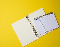open notebook in a cage with white blank sheet and on a yellow background, top view photo