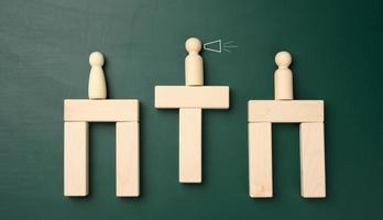 wooden figures of men on a bridge made of bars, in the middle there is a negotiator. photo