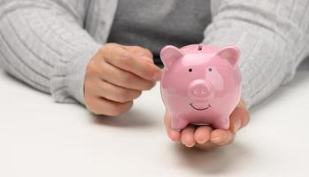 female hands are holding a pink ceramic piggy bank. Accumulation concept, budget control photo